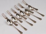 six silverplated forks and spoons are lined up on a white surface