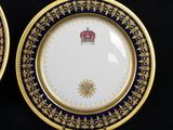 two gold and blue plates with a crown on them on a black surface