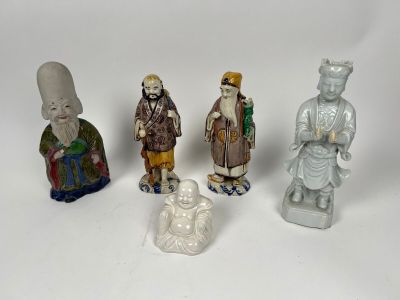 Plusieurs figurines représentant des personnes d'origine asiatique sont alignées sur une surface blanche.