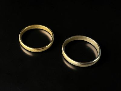 two gold wedding rings on a black surface