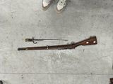 un pistolet et un fusil posés par terre à côté d'une paire de chaussures
