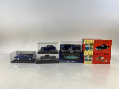 trois petites voitures sont exposées dans une vitrine posée sur une surface blanche