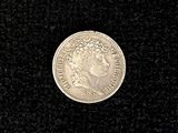 an old silver coin on a black surface with a black background