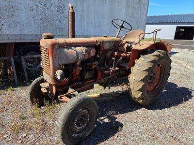 a rusted old tractor parked in front of a building