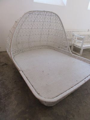 un lit en osier blanc dans une pièce avec des chaises blanches
