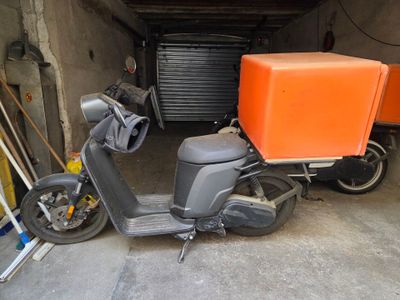 un scooter avec un coffre à l'arrière, dans un garage