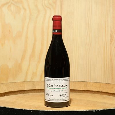 a bottle of wine sitting on top of a barrel