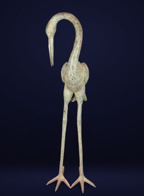 a bronze statue of a bird with long legs and a long neck