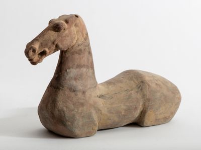 une petite statue représentant un cheval assis sur une surface blanche
