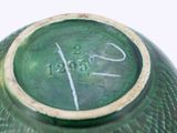 a green vase with writing on it sitting on a table