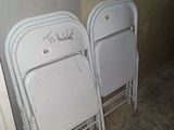 two white folding chairs with writing on them in the corner of a room