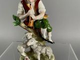 a figurine of a boy sitting on a rock playing a flute