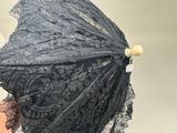 une femme tenant un parapluie en dentelle noire à la main