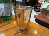 a silver cup sitting on a wooden table next to a bottle of water