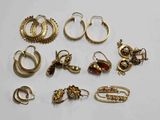 plusieurs paires de boucles d'oreilles et de bagues en or posées sur un fond blanc