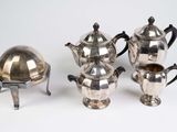four pieces of silverware including a teapot, coffee pot, and tray