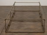 a metal bed frame with a glass top on a wooden floor