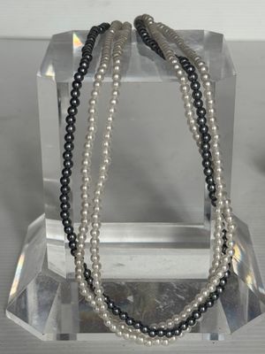 deux rangées de perles noires et blanches présentées sur un présentoir transparent