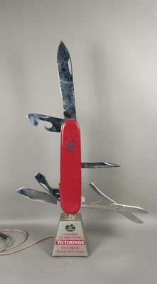 a swiss army knife with a red handle on a stand