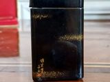 a black lighter sitting on a wooden table next to a red box