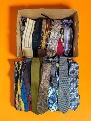 many different ties in a box on a yellow background