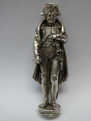 statue en argent représentant un homme coiffé d'un chapeau et vêtu d'un manteau, tenant une épée