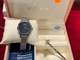 une photo d'une montre dans un coffret posée sur un tapis rouge