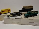 trois camions miniatures posés sur des cartons posés sur une table