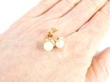 a woman ' s hand holding a pair of pearl earrings