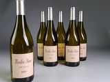 six bouteilles de vin blanc sont alignées sur une table
