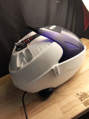 un aspirateur blanc et violet posé sur une table en bois