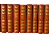 six red books with gold covers are lined up on a white surface
