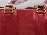 red leather handbag with gold handles and a clear plastic handle