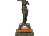 une statue antique en bronze représentant une femme, posée sur un socle en marbre
