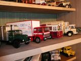 de nombreux camions miniatures posés sur une étagère dans une pièce