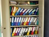 a cabinet full of files and binders in the corner of a room