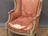 une vieille chaise dont l'assise est recouverte d'un tissu rouge