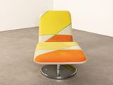 an orange and yellow chair sitting on top of a cement floor