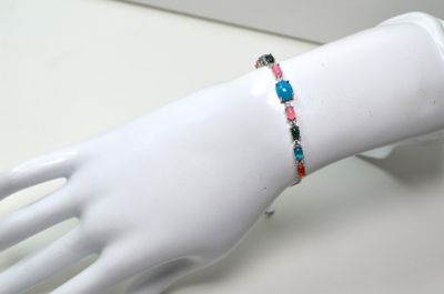 une main de mannequin blanche ornée d'un bracelet coloré