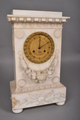une horloge blanche avec un cadran doré, posée sur un socle