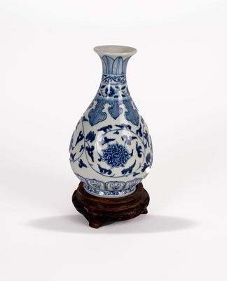 un vase bleu et blanc posé sur un support en bois