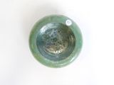 a green bowl sitting on a table with a white background