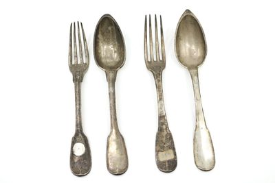 trois cuillères en argent et une fourchette sont posées les unes à côté des autres