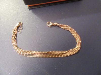 un bracelet en chaîne d'or posé sur une table, à côté d'un portefeuille