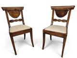 deux chaises en bois avec des assises rembourrées beiges et un coussin blanc