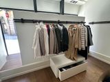 an image of a closet with clothes hanging on a rail