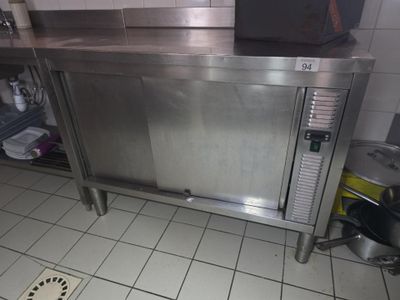 un plan de travail en acier inoxydable dans une cuisine, avec une casserole posée par terre