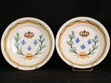 two plates with blue flowers and a crown on them on a black background