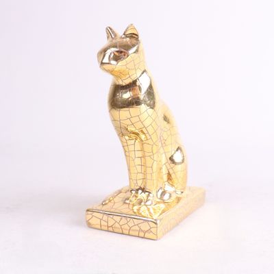une statue en or représentant un chat assis sur une surface blanche
