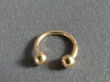 a close up of a gold nose ring with two balls on it
